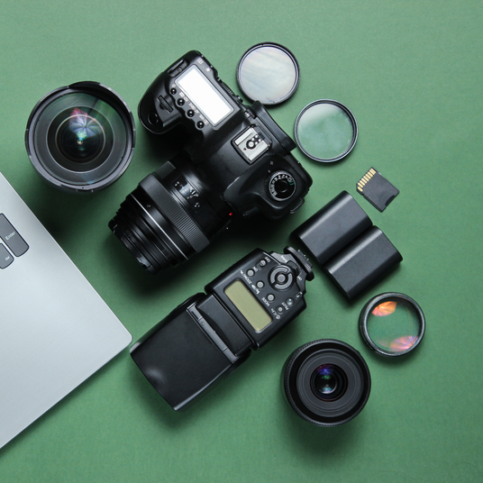 overhead photo of dslr camera, flash, lenses, filters, batteries, and memory card